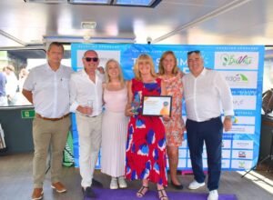Helen standing with CleanTEC colleagues, smiling and holding her Cleaning Operative of the Year award.