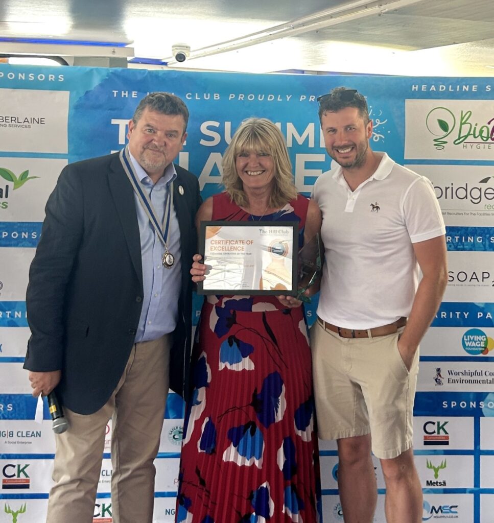 Helen standing between two award presenters as she receives her Cleaning Operative of the Year award at the Cleaning Industry Awards 2025.